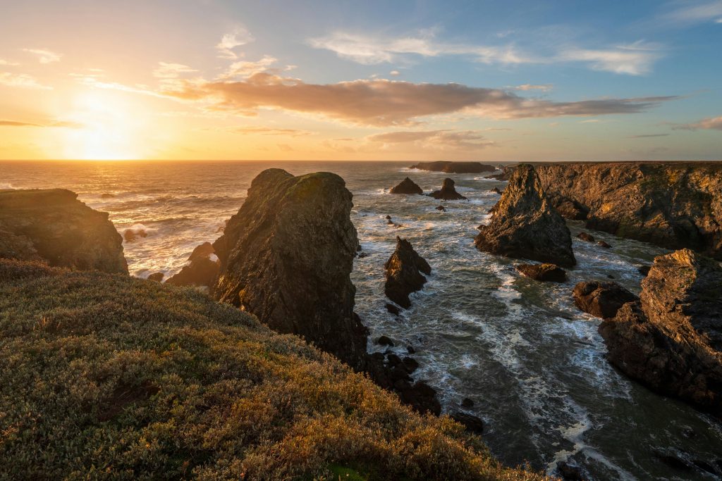 Capture the stunning beauty of a rocky coastline at sunset in Bretagne, France.
